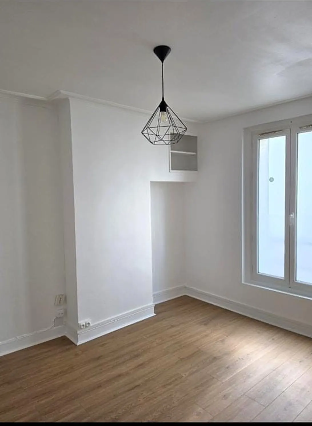 Chambre après rénovation — murs blancs, parquet neuf, luminaire design